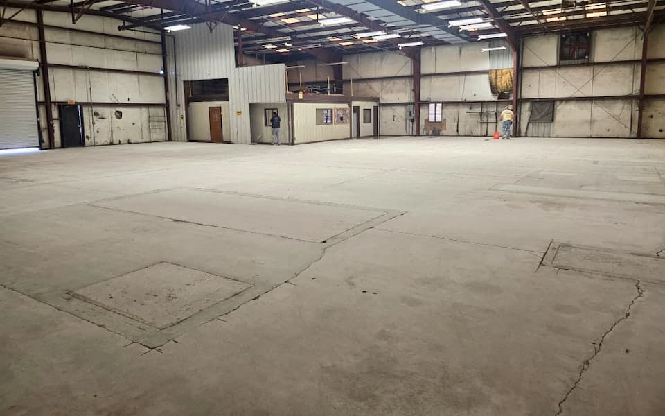 Original cracked concrete slab before epoxy flooring at the JAXPORT body shop